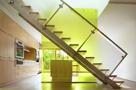Au premier plan, on voit le garde-corps en verre trempé au fini givré de l'escalier, qui mène au quartier des parents. Ce lieu regroupe la chambre principale, une salle de bains, un cabinet de toilette et un bureau. Le panneau de verre à double paroi filtre la lumière naturelle et sa couleur jaune chartreuse «avive» la verdure du jardin tout en dynamisant l'environnement. La main courante est en acier inoxydable. Au premier plan, on voit le garde-corps en... (Photo fournie par Yves Lefebvre)