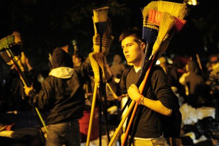Des manifestants anti-Wall Street distribuent des balais à... (Photo: Emmanuel Dunand, AFP)