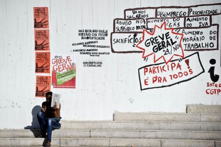 Austérité: une grève générale paralyse le Portugal Une femme est assise à proximité d'un graffiti... (Photo: Patricia de Melo Moreira, AFP)