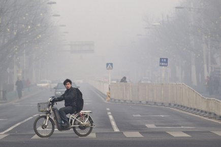 Un Pékinois conduit sa mobilette dans une rue... (Photo: Andy Wong, AP)