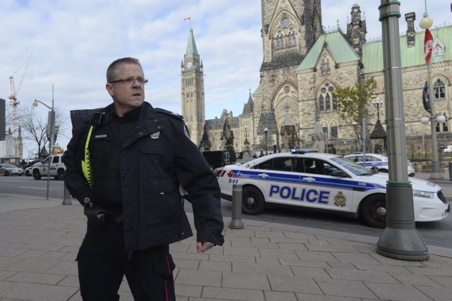 Les députés du SLSJ en sécurité A police officer secures the scene of a... (Adrian Wyld, La Presse Canadienne)