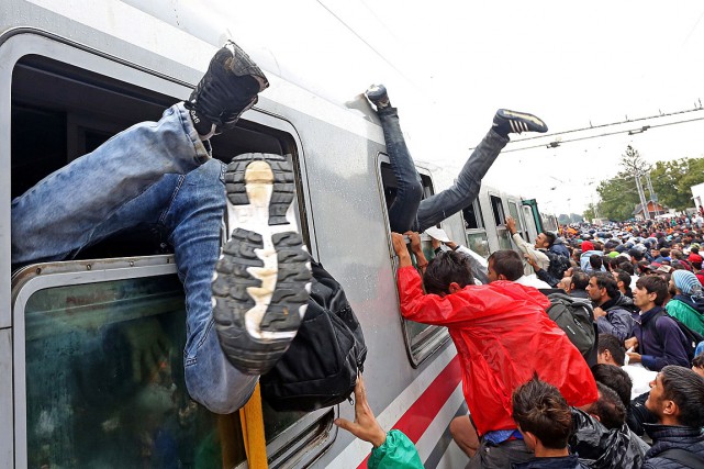Des migrants se bousculent pour monter à bord... (PHOTO AFP)