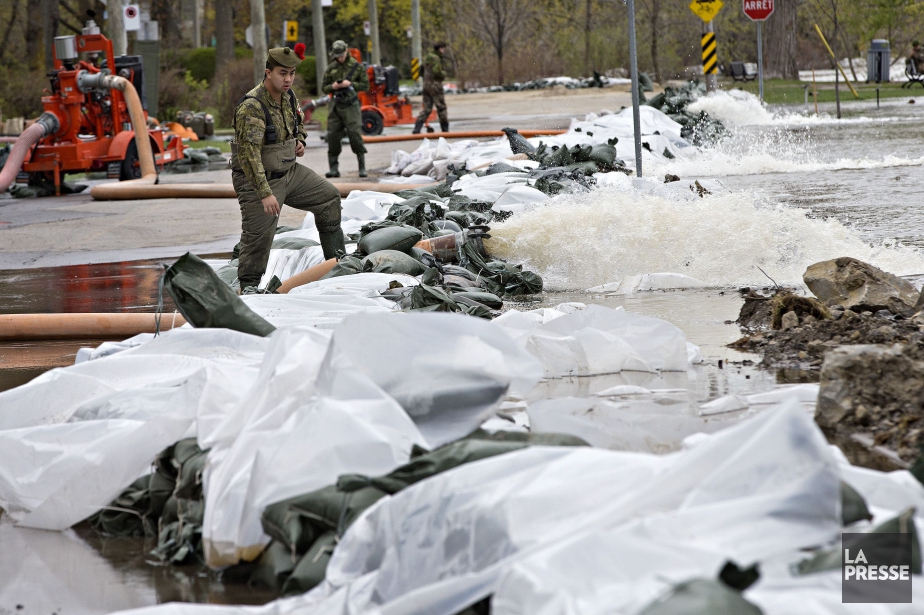 Des militaires surveillent une digue sur la rue... (PHOTO PATRICK SANFACON, LA PRESSE)